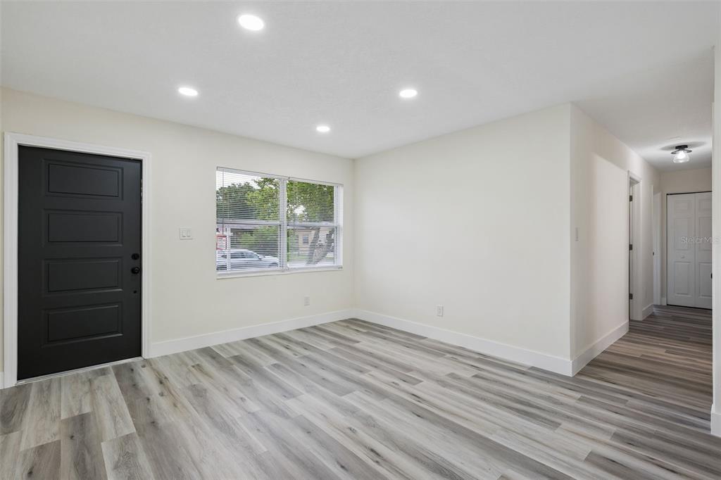 An empty room features light-colored wood-look flooring, white walls, recessed lighting, and a black door — 726 CORNELIA COURT, ORLANDO, FL