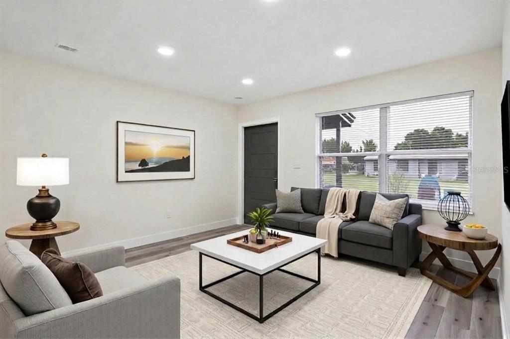 A living room features a gray sofa, a white coffee table, and light wood flooring — 726 CORNELIA COURT, ORLANDO, FL