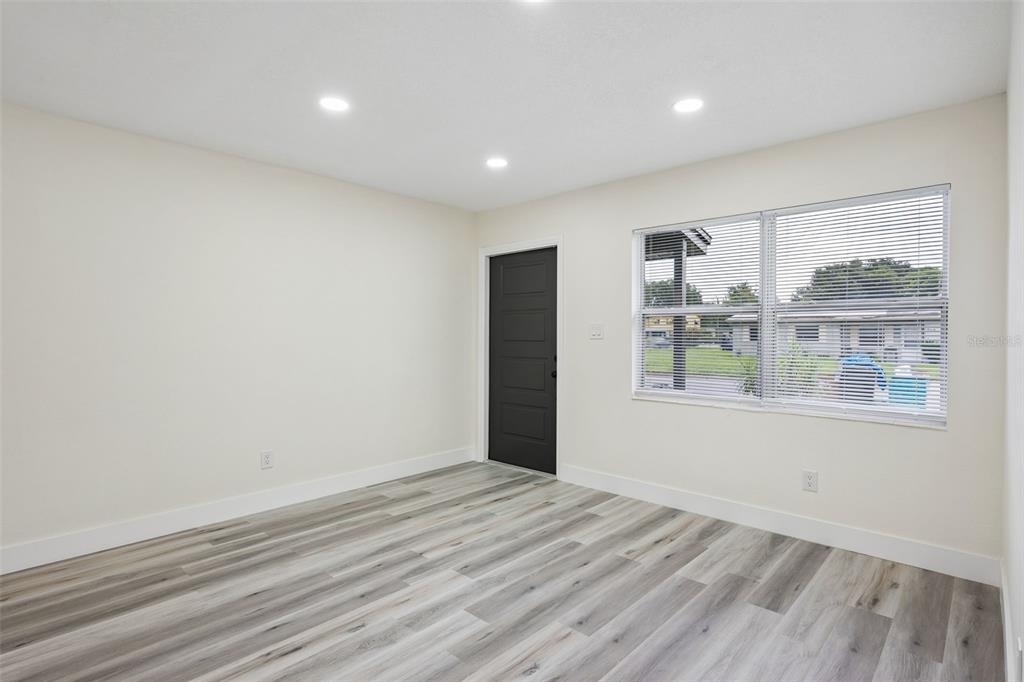 An empty room with light-colored walls, gray wood-look flooring, recessed lighting, and a black door — 726 CORNELIA COURT, ORLANDO, FL