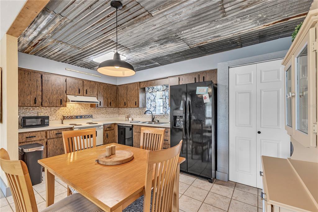A kitchen with wood cabinets, a corrugated metal ceiling, and a wooden dining table — 1640 JUNO TRAIL UNIT 205C, ASTOR, FL