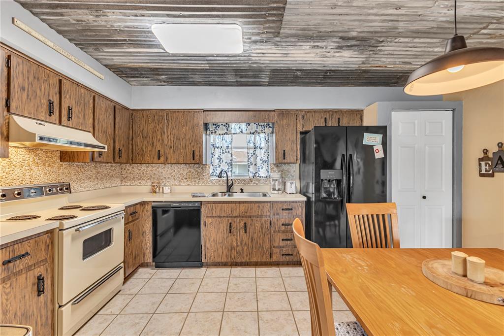 A kitchen features wood-grain cabinets, a corrugated metal ceiling, and a black refrigerator — 1640 JUNO TRAIL UNIT 205C, ASTOR, FL