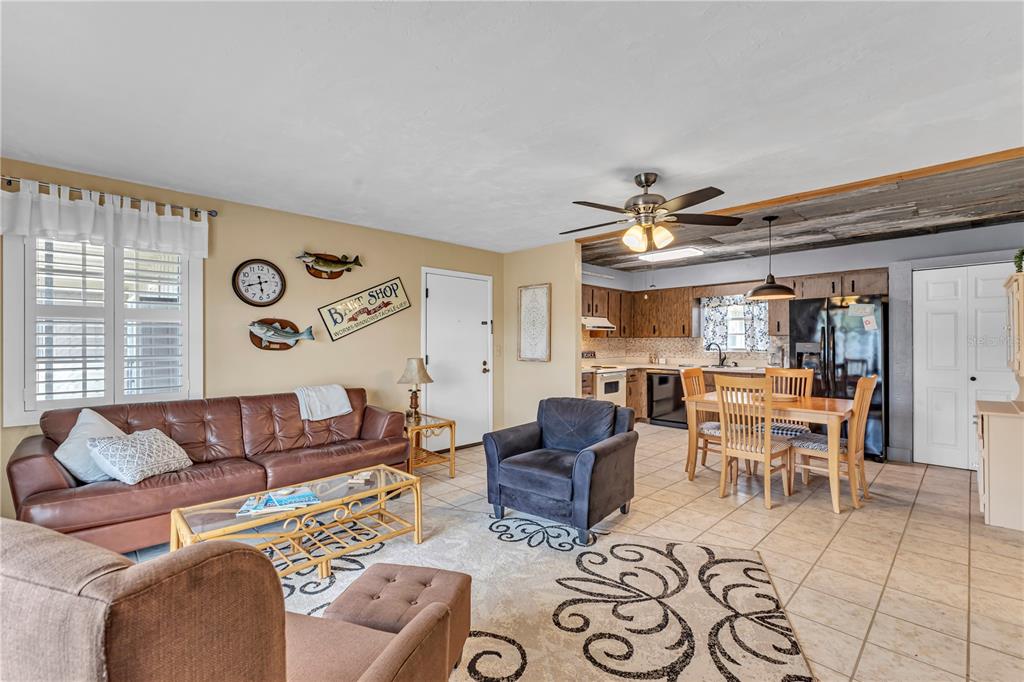 A living room with a brown leather sofa, tiled floors, and an open-concept kitchen — 1640 JUNO TRAIL UNIT 205C, ASTOR, FL