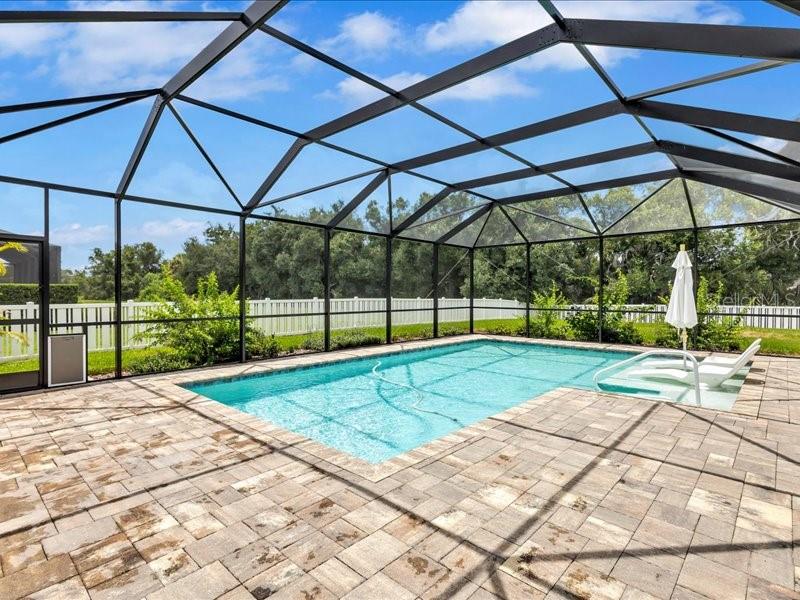 A covered patio features a wood-plank ceiling, ceiling fans, stone pavers, and glass French doors — 1436 HICKORY VIEW CIRCLE, PARRISH, FL