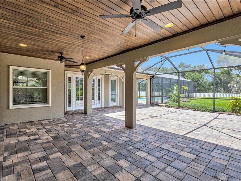 A covered patio with paver flooring, wooden ceiling, and a screened-in enclosure overlooking a yard — 1436 HICKORY VIEW CIRCLE, PARRISH, FL