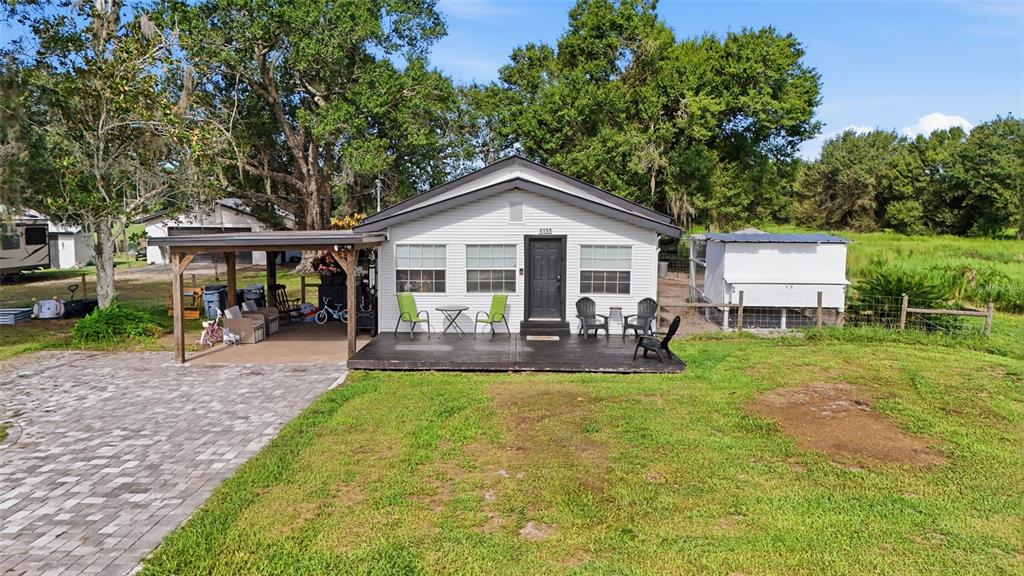 A white house with a dark roof, front deck, and attached carport sits on grass — 5135 SW SMITH AVENUE, ARCADIA, FL