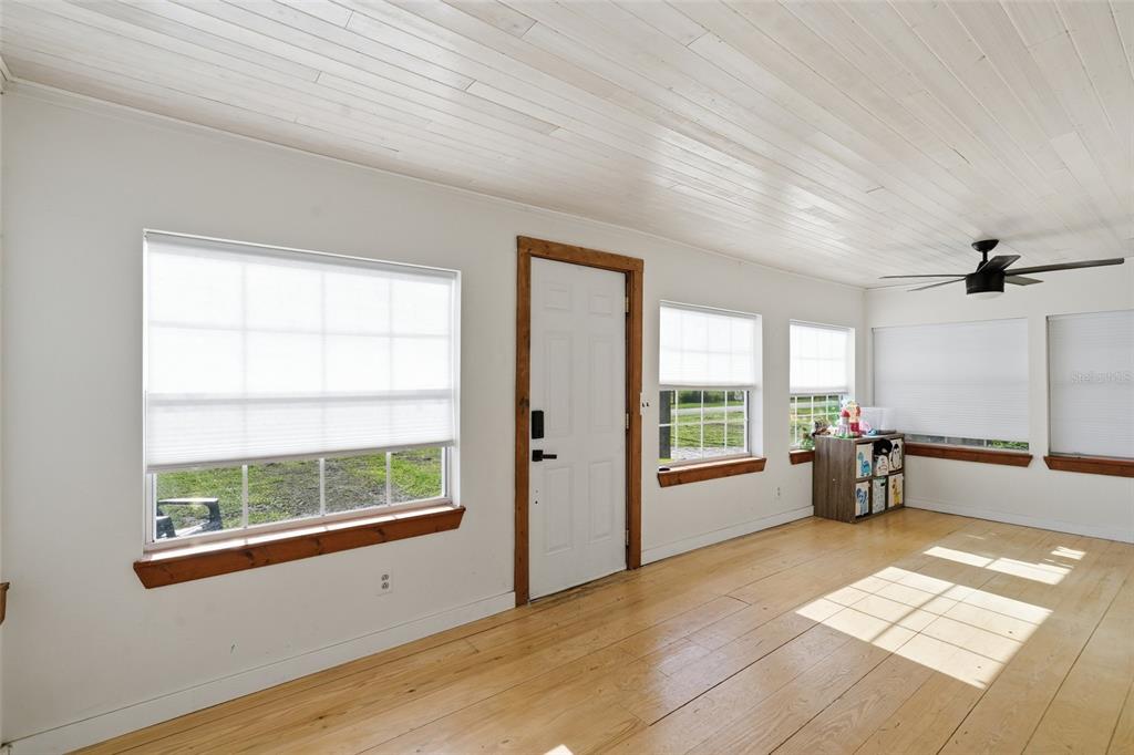 A sunroom with light wood flooring, white paneled ceilings, and multiple windows with white shades — 5135 SW SMITH AVENUE, ARCADIA, FL