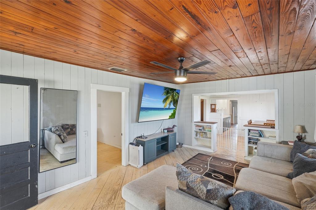 A living room features wood-plank ceilings, light-colored walls, a ceiling fan, and a television — 5135 SW SMITH AVENUE, ARCADIA, FL