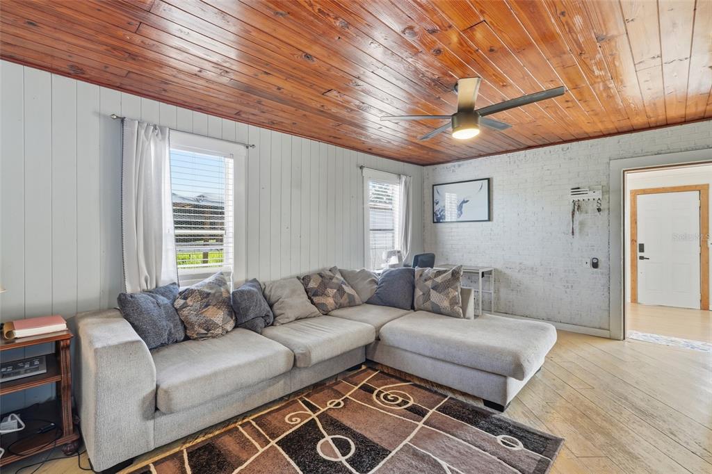 A living room features a sectional sofa, wood-paneled ceiling, and a white painted brick wall — 5135 SW SMITH AVENUE, ARCADIA, FL