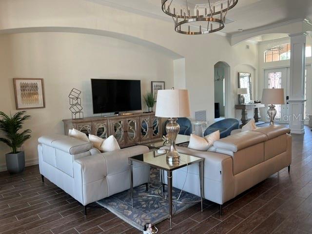 A living room features light-colored sofas, a television on a console, and a large chandelier — 5528 ARNIE LOOP, LAKEWOOD RANCH, FL