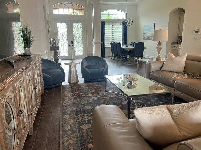 A living room features a wooden console, blue armchairs, a glass coffee table, and beige sofas — 5528 ARNIE LOOP, LAKEWOOD RANCH, FL