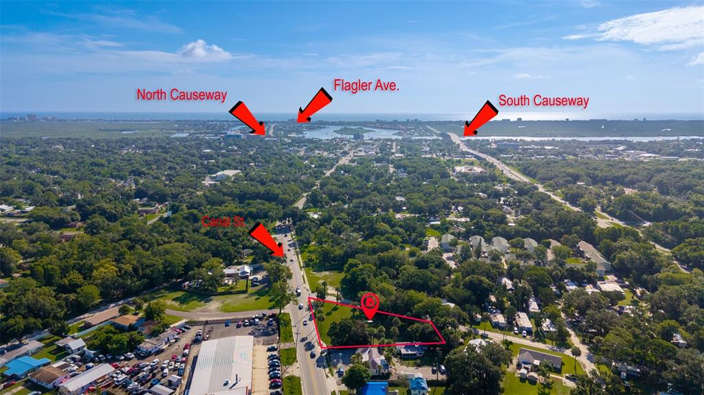 This aerial view shows a vacant lot highlighted in red near a road and causeways — 1104 CANAL STREET, NEW SMYRNA BEACH, FL