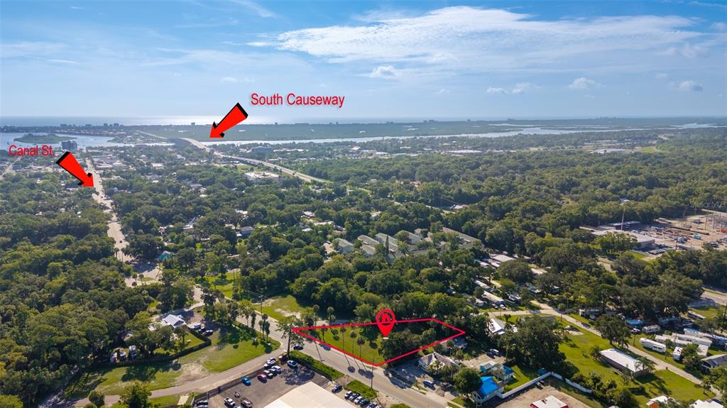 An aerial view shows a vacant lot outlined in red near a road and trees — 1104 CANAL STREET, NEW SMYRNA BEACH, FL