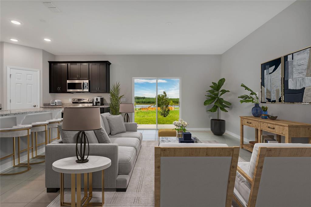 This living room features a gray sofa, two armchairs, and an open kitchen with dark cabinets — 717 CROWN ROSE DRIVE, EAGLE LAKE, FL