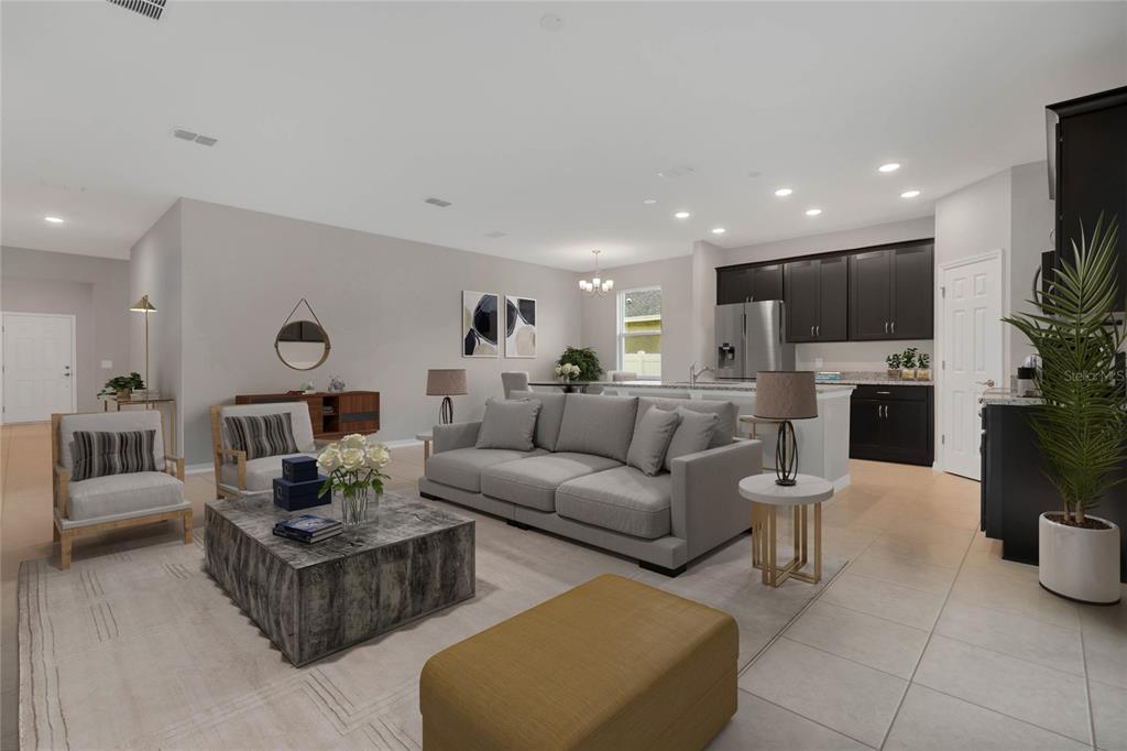 An open-concept living room and kitchen featuring gray furniture, a stone coffee table, and cabinetry — 717 CROWN ROSE DRIVE, EAGLE LAKE, FL