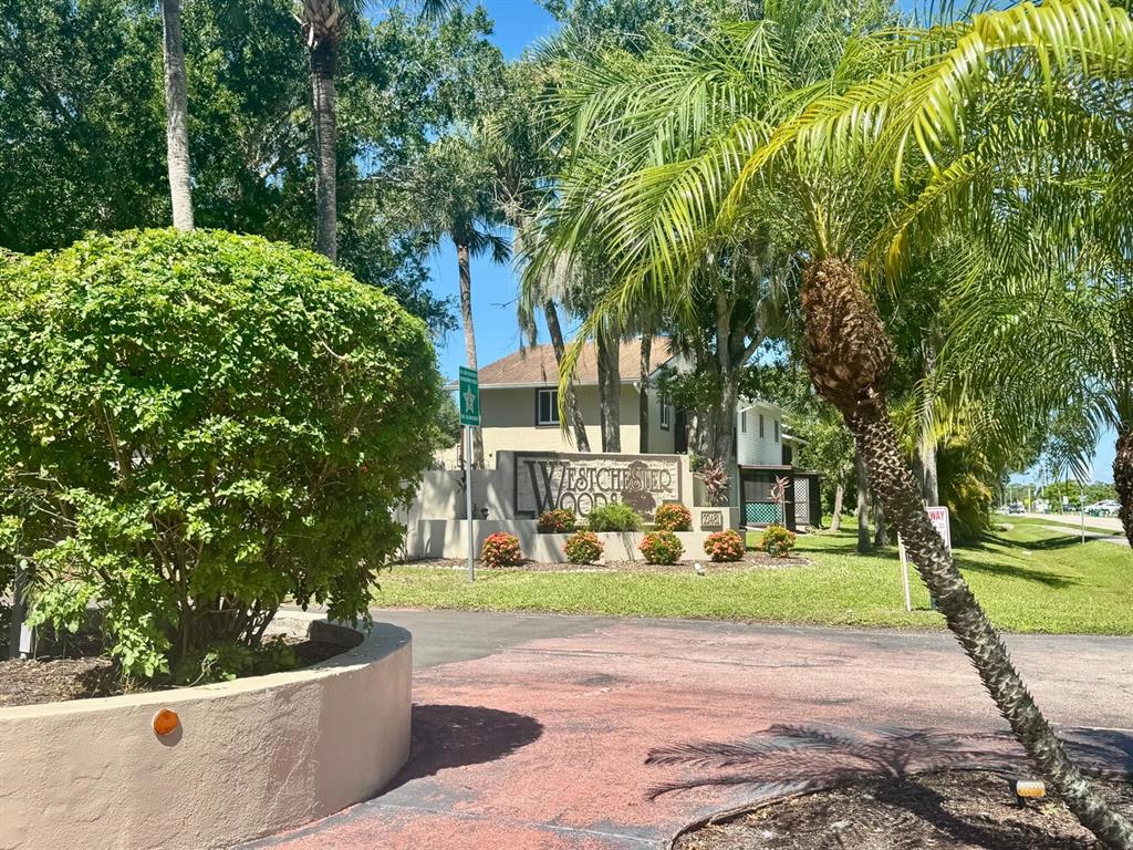 A sign for Westchester Woods stands in front of a house surrounded by palm trees — 22481 WESTCHESTER BOULEVARD UNIT B36, PORT CHARLOTTE, FL