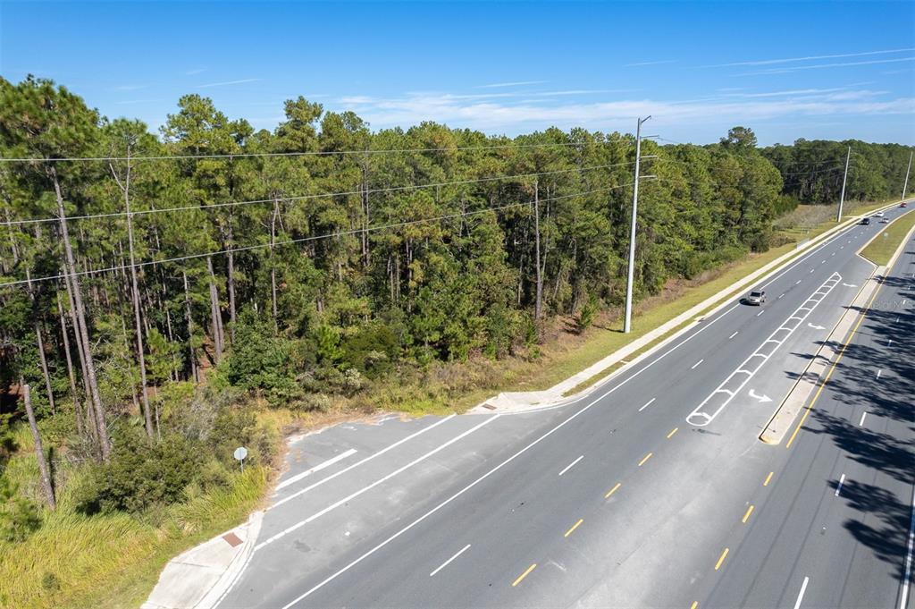 An aerial view shows a paved road running alongside a dense, wooded forest area — 00 STATE RD 20, PALATKA, FL
