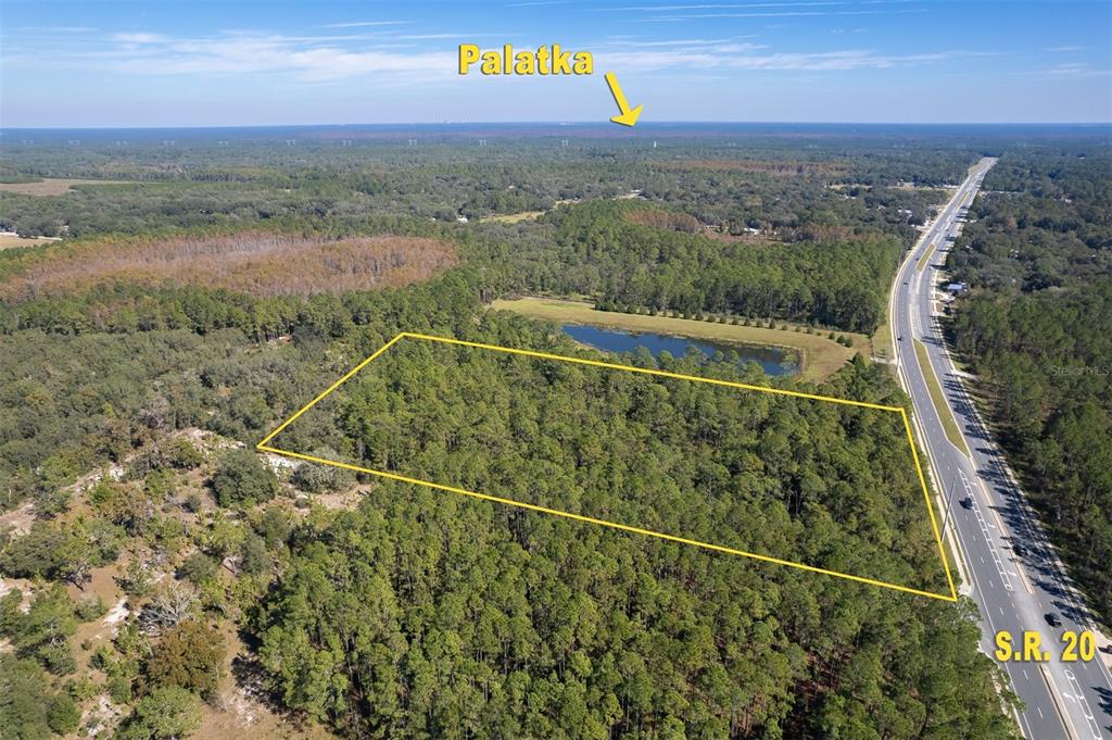 An aerial view shows a wooded lot outlined in yellow adjacent to a highway — 00 STATE RD 20, PALATKA, FL
