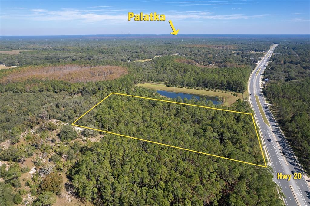 An aerial view shows a wooded lot outlined in yellow adjacent to a highway — 00 STATE RD 20, PALATKA, FL