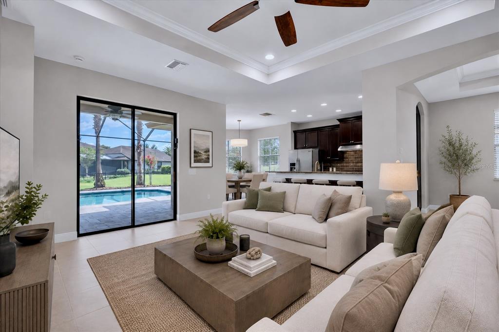 A living room with a beige sofa, coffee table, and sliding doors overlooking a pool — 8454 MAY PORT COURT, LAND O LAKES, FL