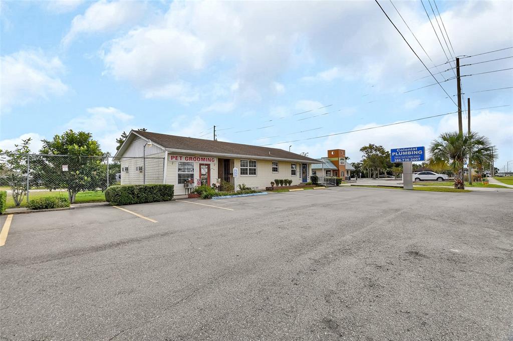 A single-story commercial building with a pet grooming sign sits next to a parking lot — 1319 S WOODLAND BOULEVARD, DELAND, FL