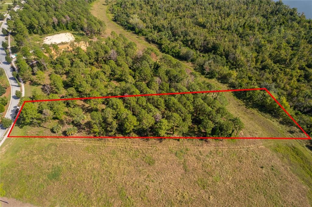 An aerial view shows a rectangular plot of land outlined in red amidst wooded areas — 16842 ARTIMINO LOOP, MONTVERDE, FL