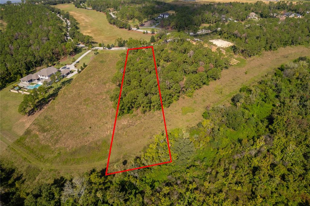 An aerial view shows a trapezoidal plot of land outlined in red amidst grassy fields — 16842 ARTIMINO LOOP, MONTVERDE, FL