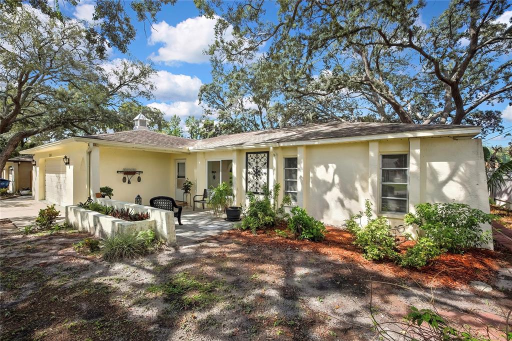 A single-story house with a light yellow exterior, a patio, and large oak trees — 1185 MACFARLANE AVENUE, SPRING HILL, FL