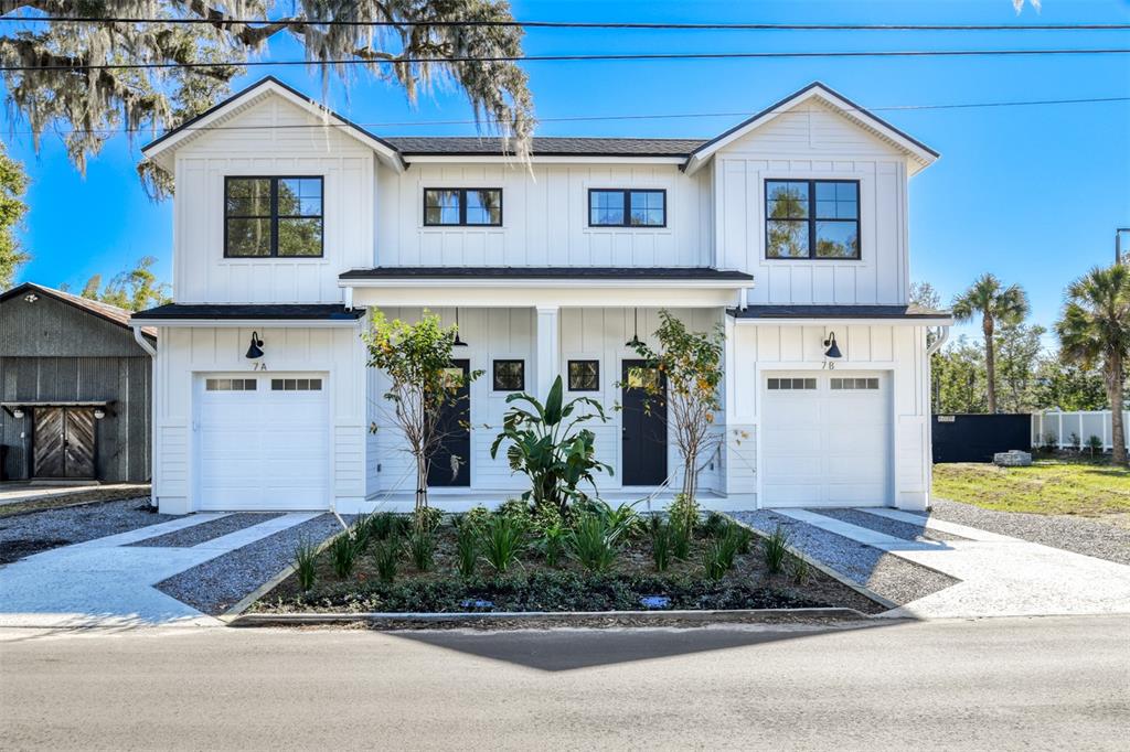 A modern two-story duplex features white board-and-batten siding, black window frames, and two garage doors — 7 SEBASTIAN AVENUE UNIT D, ST AUGUSTINE, FL