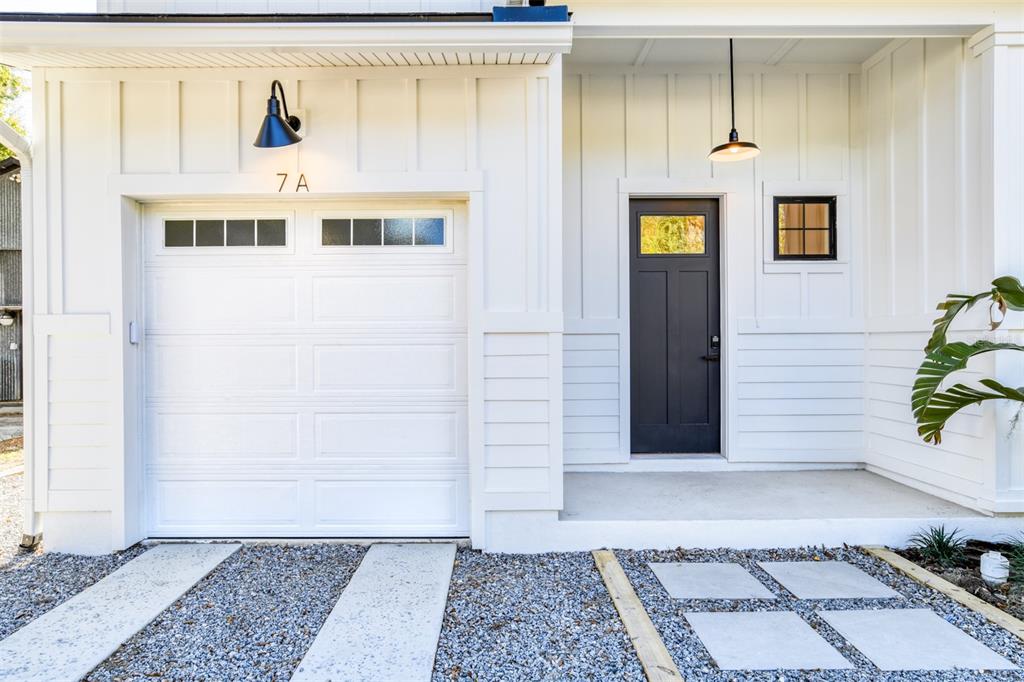 A white house exterior features a garage, a dark front door, and a gravel driveway — 7 SEBASTIAN AVENUE UNIT D, ST AUGUSTINE, FL