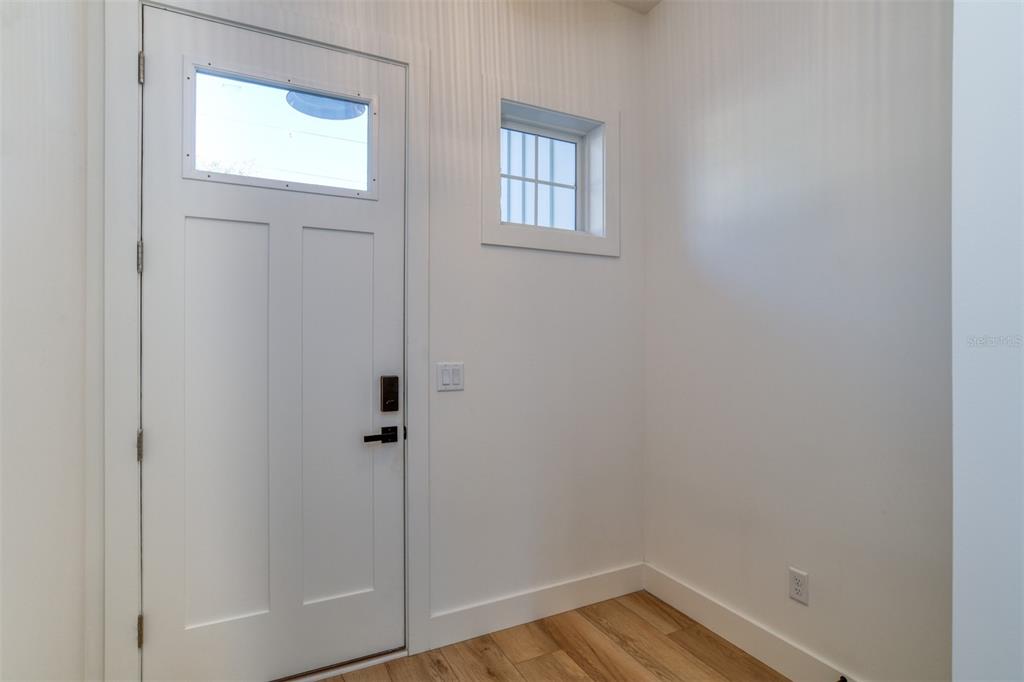 A white door with a window and black hardware sits beside a small square window — 7 SEBASTIAN AVENUE UNIT D, ST AUGUSTINE, FL