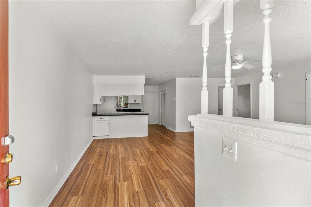 A view from a doorway looking into a kitchen with white cabinets and wood flooring — 2304 INDIA PALM DRIVE, EDGEWATER, FL