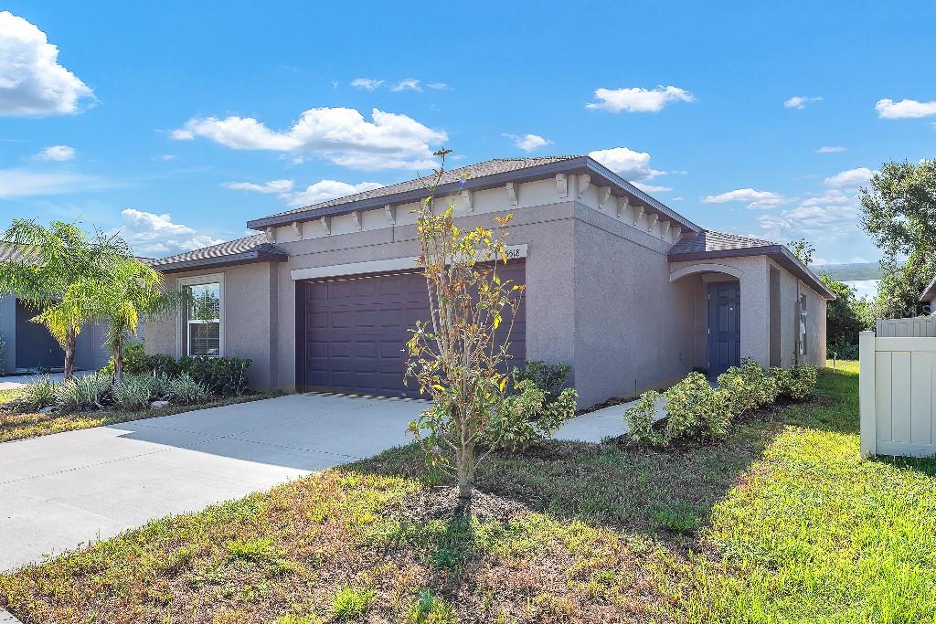 A single-story house with a stucco exterior, a two-car garage, and a front entryway — 5518 BLUE AZURE DRIVE, WIMAUMA, FL