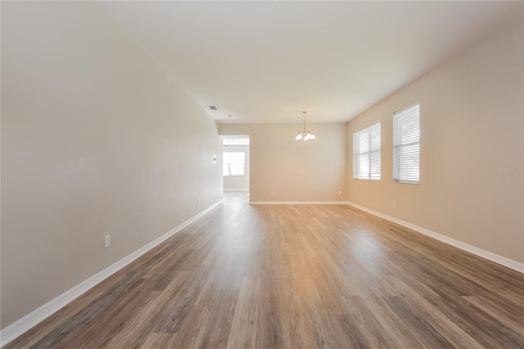 An empty room with light-colored walls, wood-look flooring, and a chandelier — 5061 GANDROSS LANE, MOUNT DORA, FL