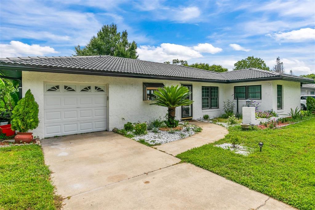 A single-story white house with a dark tiled roof, garage, and a front walkway — 10611 DEERGRASS LANE, ORLANDO, FL
