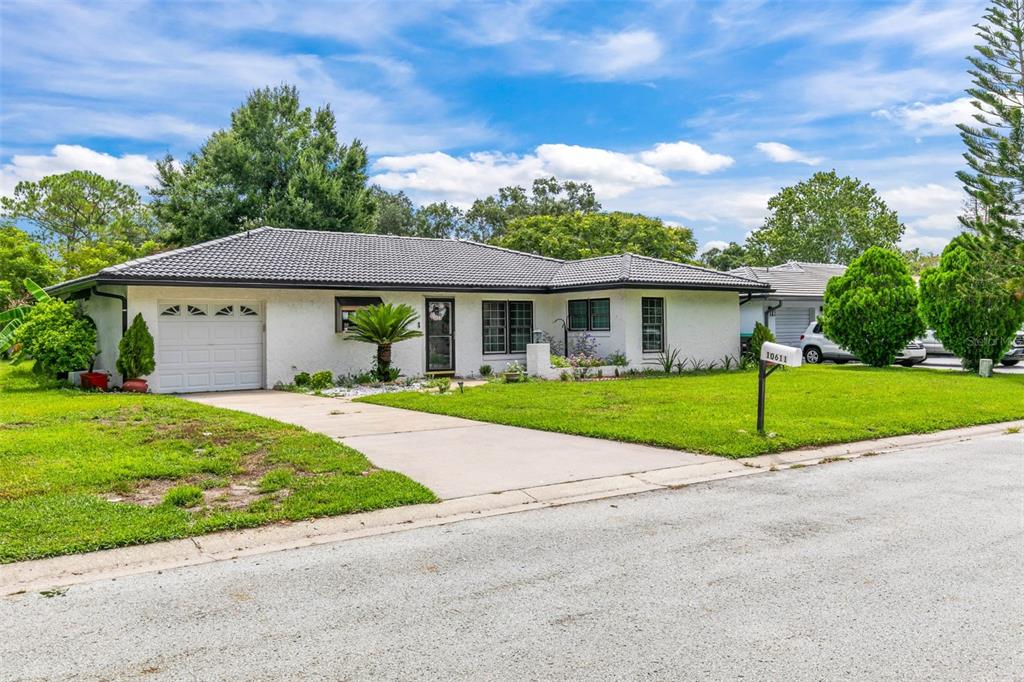 A single-story white house with a dark tiled roof and a concrete driveway — 10611 DEERGRASS LANE, ORLANDO, FL