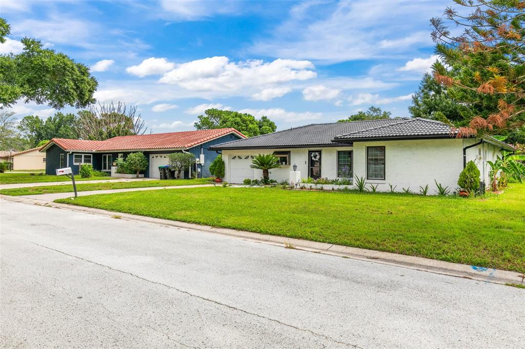 A white single-story house with a dark roof sits next to a house with red tiles — 10611 DEERGRASS LANE, ORLANDO, FL