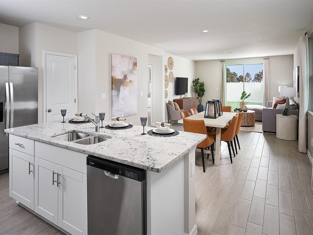 A kitchen island with granite countertops overlooks an open-concept dining and living area — 7450 MIA VINE DRIVE, BROOKSVILLE, FL