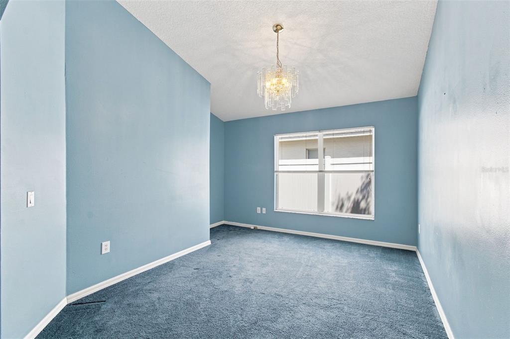 An empty room with blue walls, blue carpeting, and a crystal chandelier — 3838 BELLEWATER BLVD, RIVERVIEW, FL