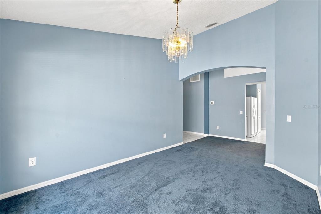 A room with blue walls, blue carpeting, and a crystal chandelier hanging from the ceiling — 3838 BELLEWATER BLVD, RIVERVIEW, FL