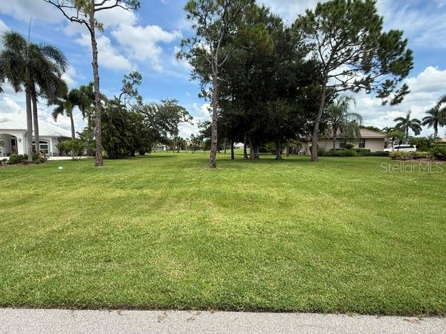 A grassy vacant lot features several mature trees and palm trees under a cloudy sky — 3030 BIG BEND CIRCLE, PUNTA GORDA, FL