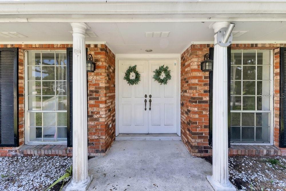 A brick house entrance features a white double door with wreaths and two white columns — 460 HARBOUR ISLAND ROAD, ORLANDO, FL