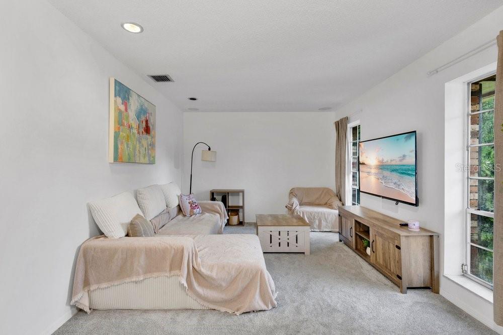 A living room with a sectional sofa, television, media console, and a large window — 460 HARBOUR ISLAND ROAD, ORLANDO, FL