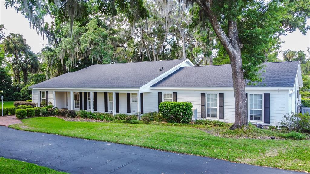 A single-story white house with black shutters and a dark shingled roof sits behind trees — 3515 SW 24TH AVENUE ROAD, OCALA, FL