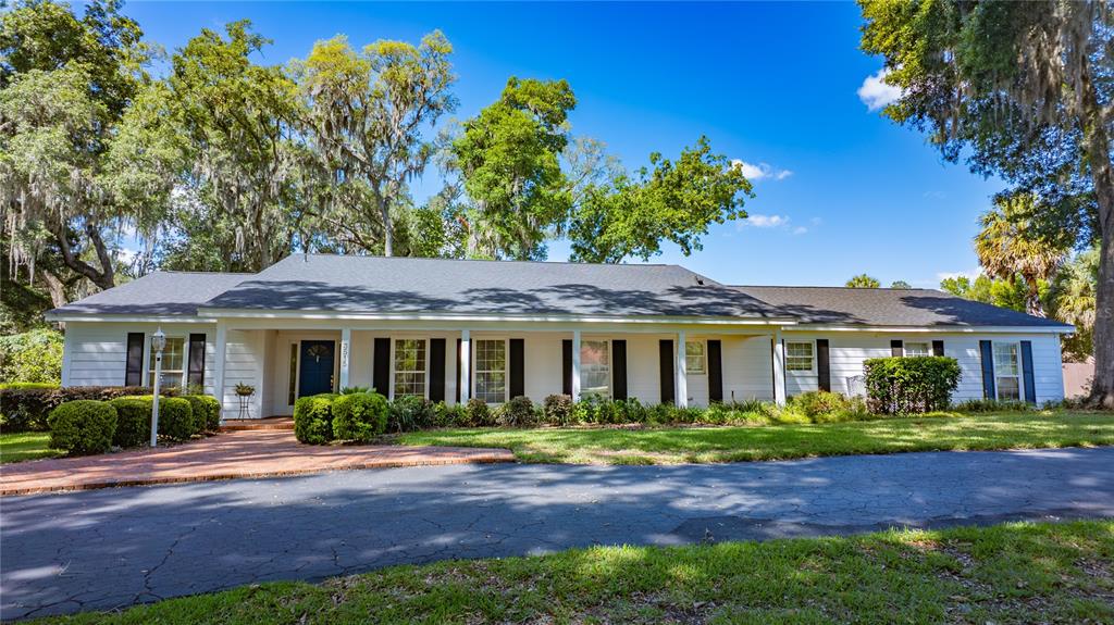 A single-story white house with black shutters and a dark roof sits behind a driveway — 3515 SW 24TH AVENUE ROAD, OCALA, FL