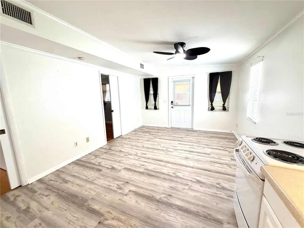 A white kitchen features a stove, sink, refrigerator, and light wood-look flooring — 516 NORTHMOOR AVENUE N, ST PETERSBURG, FL
