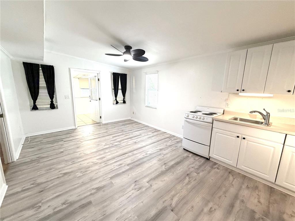 A kitchen features white cabinets, a white stove, wood-look flooring, and an adjacent doorway — 516 NORTHMOOR AVENUE N, ST PETERSBURG, FL