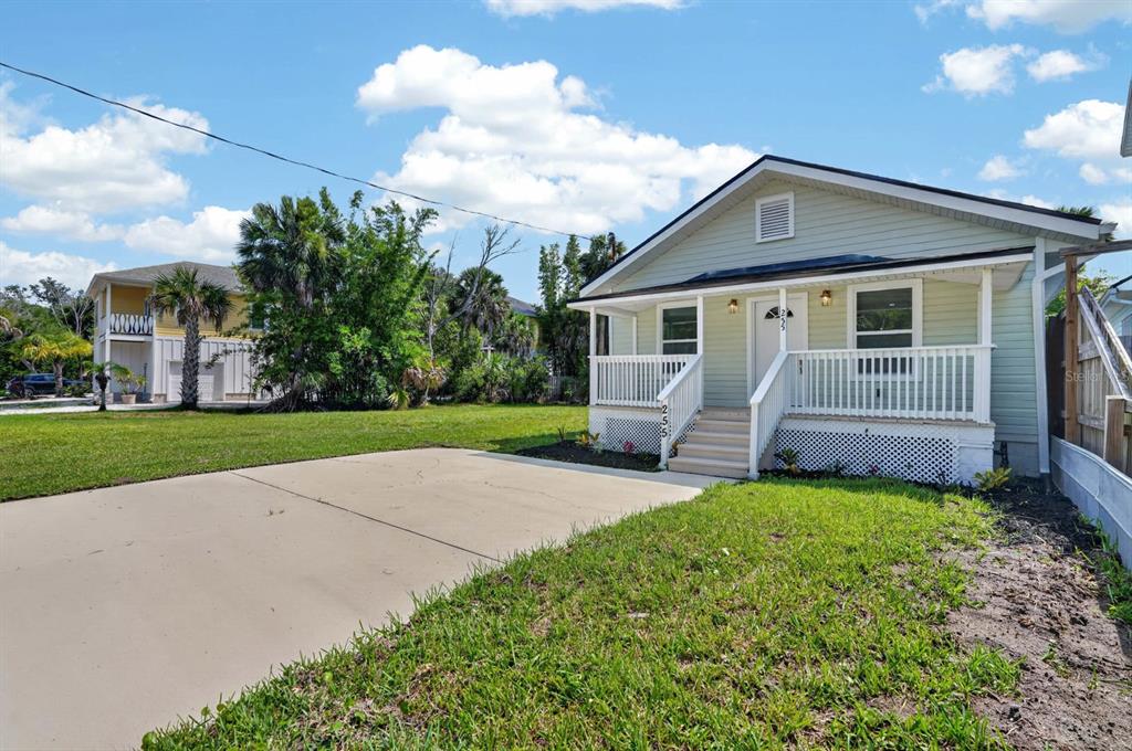 A light green house with a front porch and a concrete driveway under a blue sky — 255 RIBERIA STREET, ST AUGUSTINE, FL