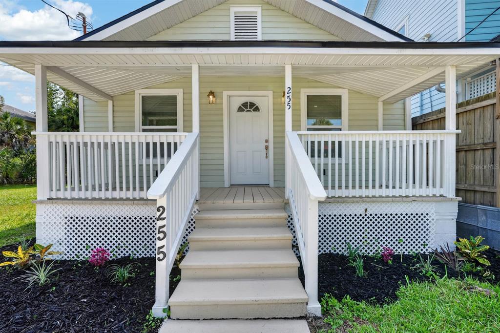 A light green house features a covered front porch with white railings and stairs — 255 RIBERIA STREET, ST AUGUSTINE, FL