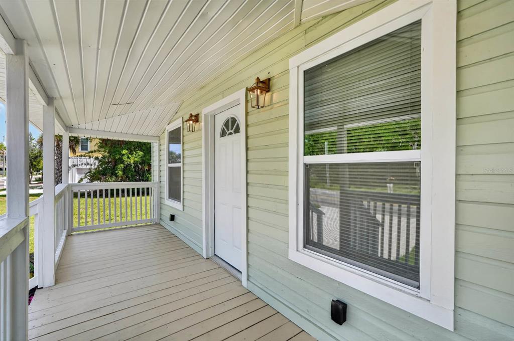 A covered porch with light green siding, a white door, and a window with blinds — 255 RIBERIA STREET, ST AUGUSTINE, FL