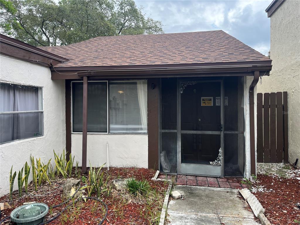 The exterior of a house features a screened-in front porch, brown trim, and a shingled roof — 12506 FOX CROFT LANE, HUDSON, FL